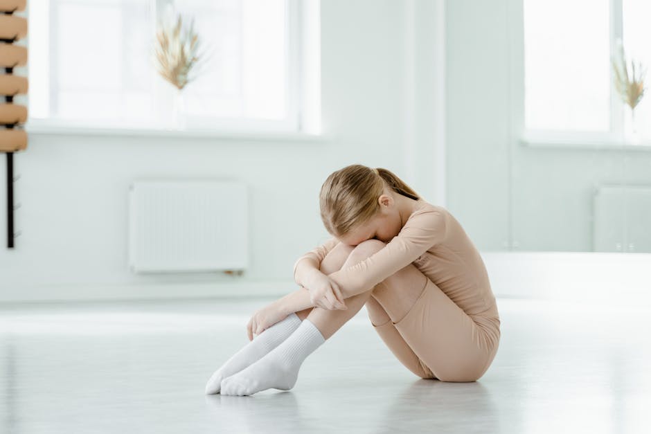 Person resting in a restorative child's pose on a yoga mat in a sunlit, minimalist room.